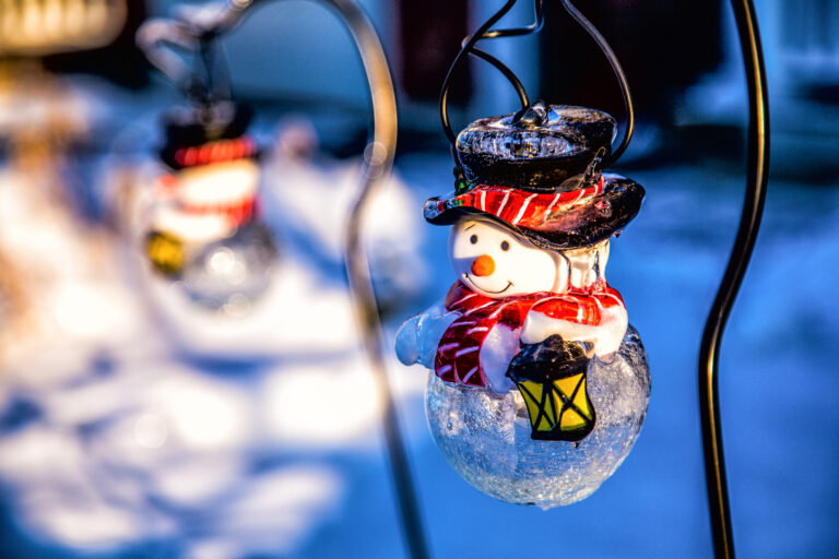 tiny snowman light holding a lantern outside in the snow